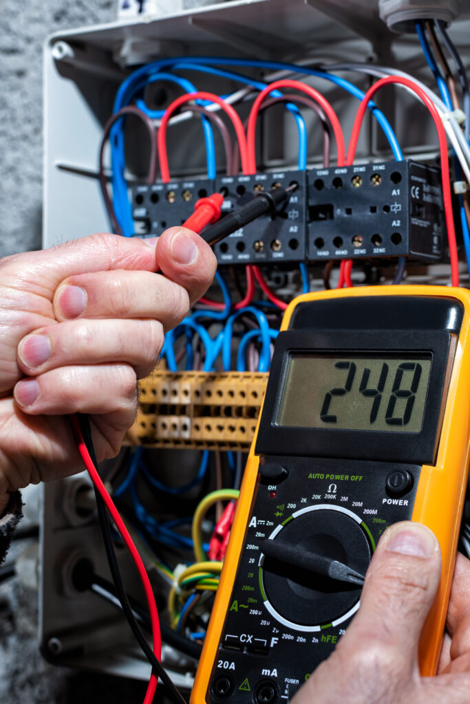 Electrician with multimeter tester measures the voltage in a residential distribution electrical panel